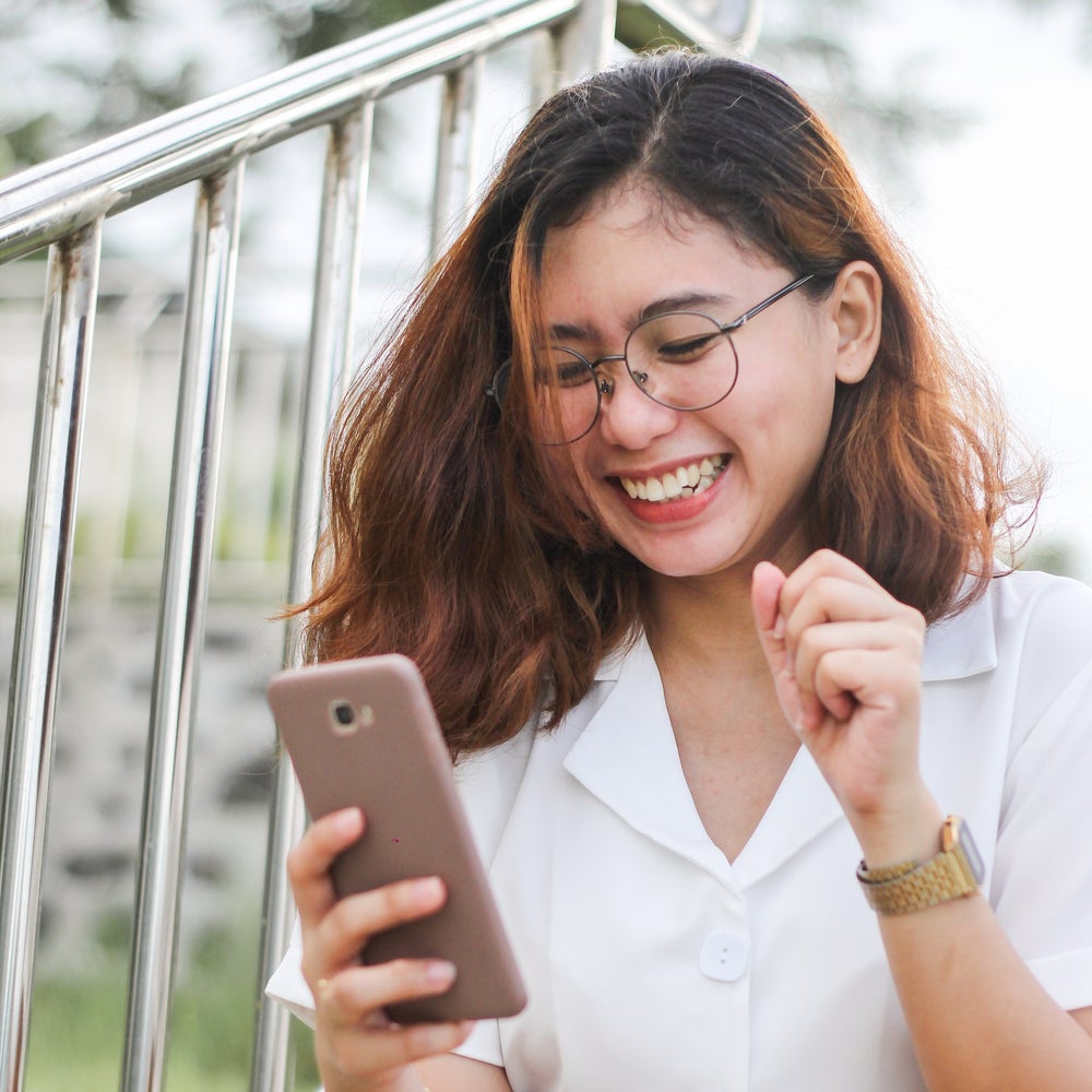 Lächelnde Reiterin fragt am Smartphone unverbindlich einen Wiegetermin an